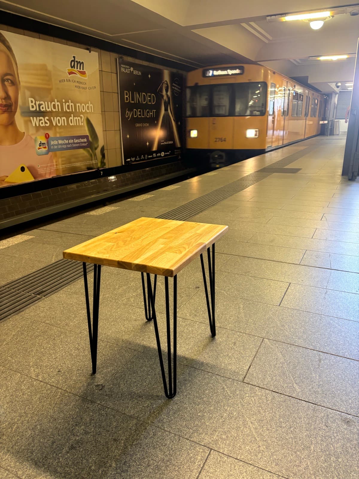 Der Standardtisch auf dem U-Bahnsteig, dahinter fährt eine gelbe U-Bahn ein
